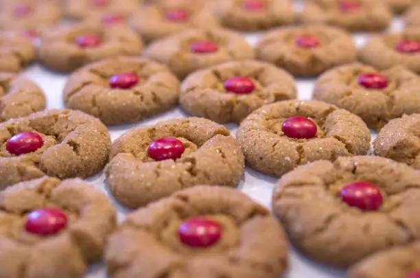 Background image of freshly backed sugar topped ginger cookies with a red chocolate center piece.