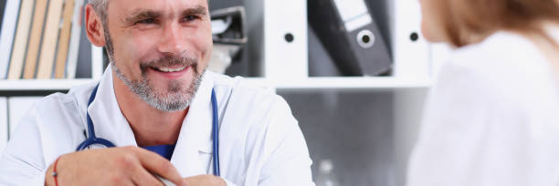 istock Smiling handsome mature doctor communicate with patient 873396430