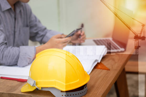 istock helmet and paper work with engineer use phone to contact business 873397282
