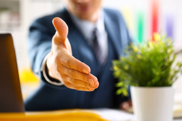 Man in suit and tie give hand as hello in office