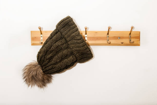 istock Winter wool cap with a furry ball hanging on a hat stand on white background 873400360