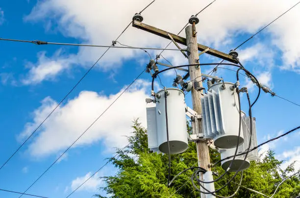 Photo of Electricity Distribution Pole with Transformers aginst Bleu Sky with Clouds