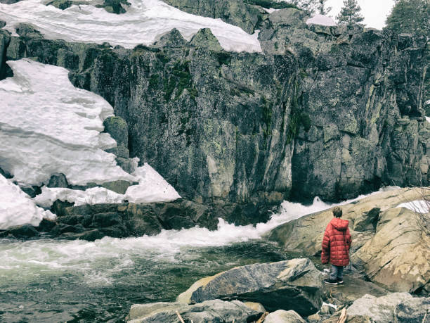 istock Boy in his dad's coat staring at a snow covered river 873409726