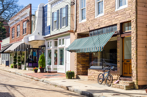 Traditional American Stores along a Cobblestone Street in the Historic District of Annapolis, MD, on a Sunny Autumn Day. There is a Bicycle Leaning against the Window of one of the Stores.