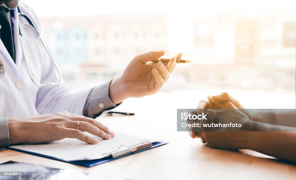 Doctor hand holding pen and talking to the patient about medication and treatment. Doctor Stock Photo