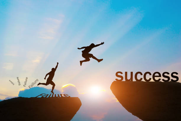 istock Men jump over silhouette failure to success. 873425970