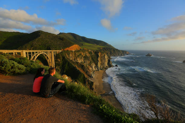 couple enjoys the ocean view A couple enjoys a pacific sunset view from bixby creek bridge on the california coast. Bixby Creek stock pictures, royalty-free photos & images