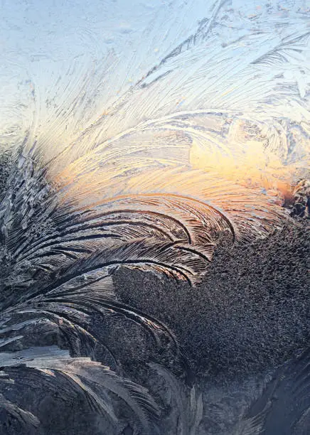 Natural ice pattern and sunlight on winter window glass