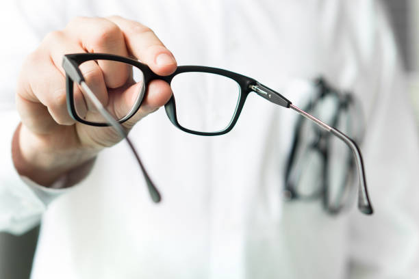 opticien, donnant de nouvelles lunettes au client pour tester et essayer. cristallins médecin montrant patients. - focal photos et images de collection