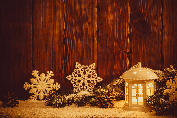 istock Christmas lantern with lit by candles, Christmas tree branches, cones, snowflakes and snow on vintage wooden background. Free space 873473730