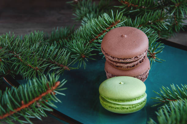 istock Fresh green and brown macaroons macaroons on Christmas table decorated with fir branches. Copy the place 873480236