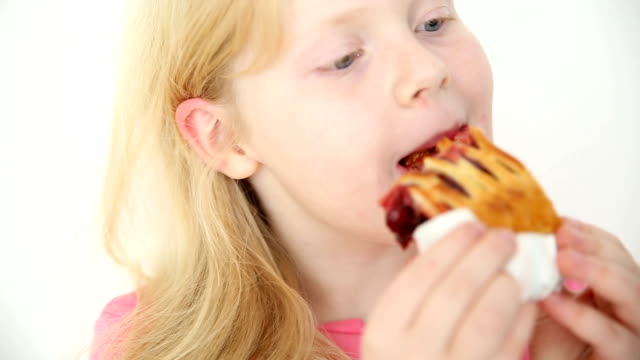 blonde girl eats cherry pie on white background close-up