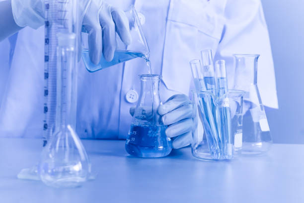 istock Blue drop into glass beaker with flask and science laboratory background 873487172
