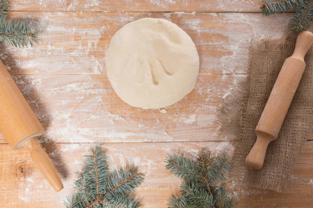 dough on a wooden board, rolling pin, branches of a Christmas tree on a table