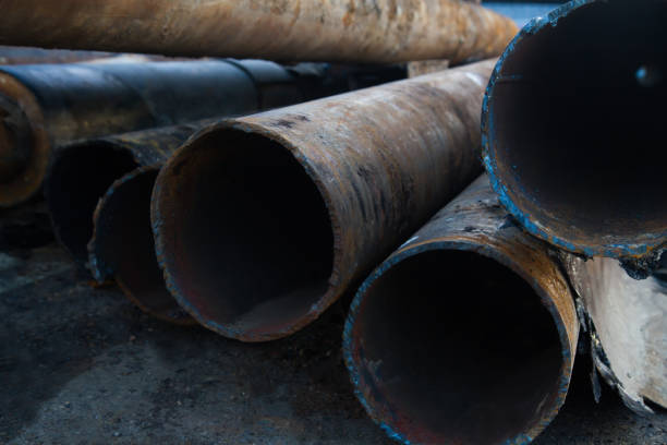 close up of a pile of large and rusting steel pipes lying close up of a pile of large and rusting steel pipes lying on the  asphalt deconstruct stock pictures, royalty-free photos & images
