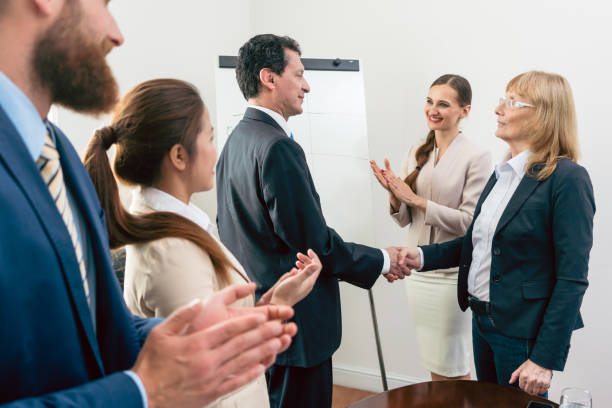 istock Two middle-aged business associates smiling while shaking hands 873512148