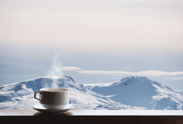 kopje warme drank met stoom op houten bureau en mooie winter landschap weergave in de ochtend - cafe snow stockfoto's en -beelden