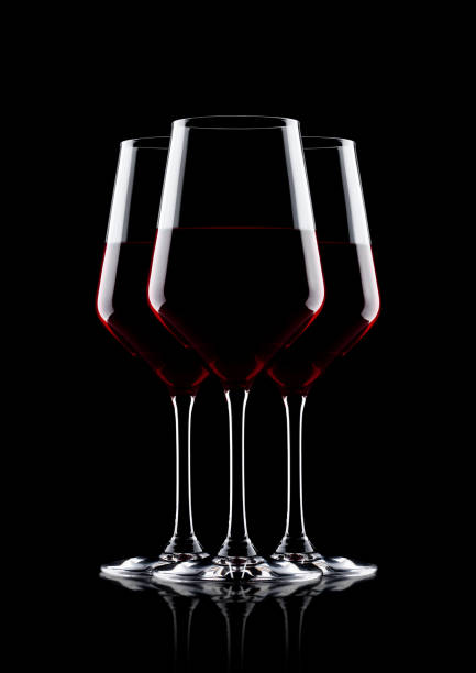 istock Glasses of red wine on black with reflection 873518736