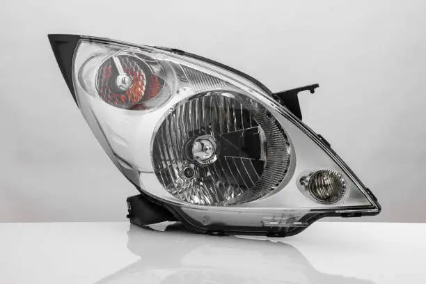 Photo of a car headlight on white background with reflection