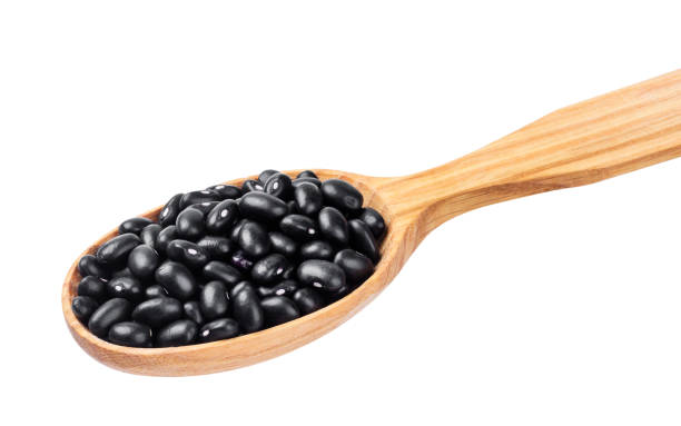 Black beans in wooden spoon isolated on white background