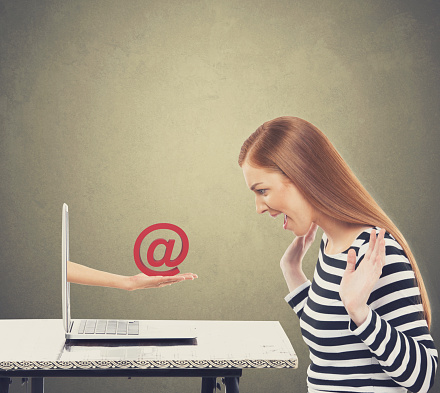Laptop with hand holding at email symbol for surprised businesswoman