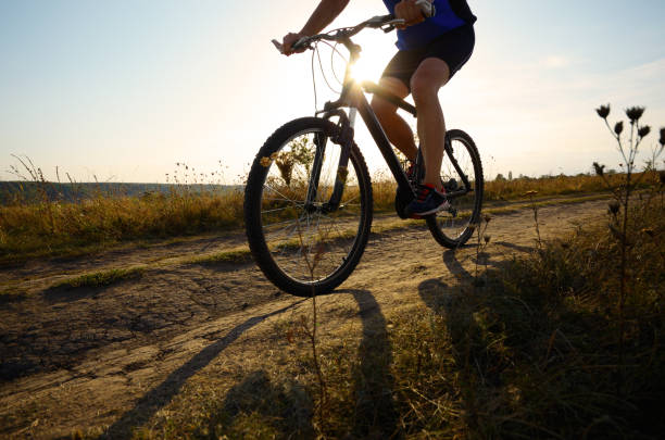 istock Male cyclist driving by rural dirt road outdoors. Low angle view 873528972
