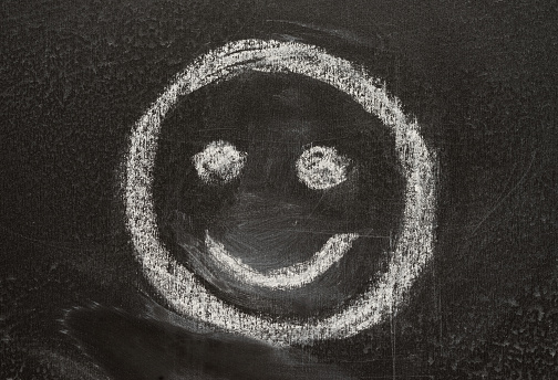smile sign smiley, sketched with white chalk on the blackboard