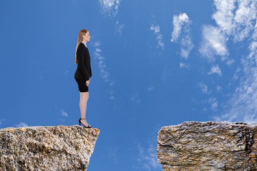 Businesswoman standing on the edge of a rocky cliff