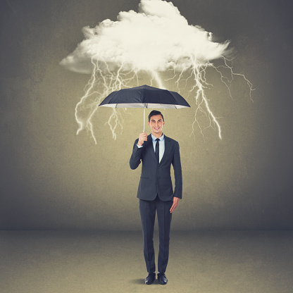 Businessman with umbrella under thunderstorm cloud