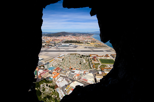 View through a hole in the Gibraltar Rock to the Gibraltar city, airport runway and La Linea town at the far end.