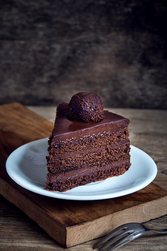 Piece of Chocolate Cake on white plate on wooden background. Homemade chocolate cake.
