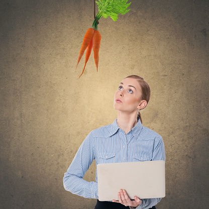 Businesswoman looking up at dangling carrot
