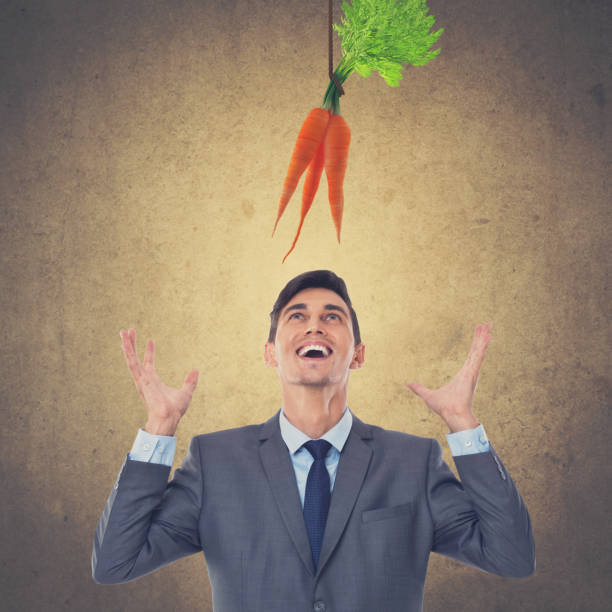 istock Excited businessman looking up at dangling carrots 873557870