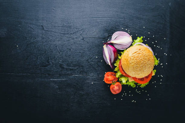 istock Hamburger with cheese, meat, tomatoes and onions and herbs. On Wooden background. Top view. Free space. 873558708