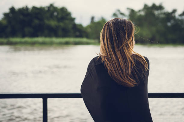 istock Lonely woman sitting and looking at the river 873558770