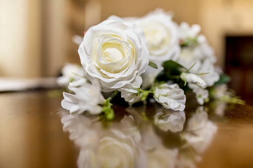 White roses wedding bouquet of flowers shot close up on a wooden table with a shallow depth of field at a tradtional English Wedding in the UK