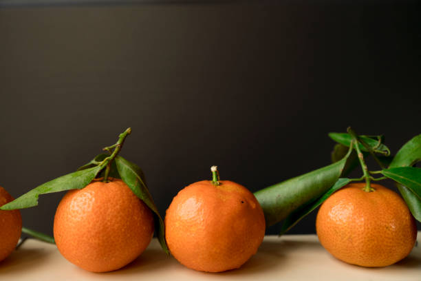 istock close up three orange mandarins with green leave with rain drops against black background 873571428