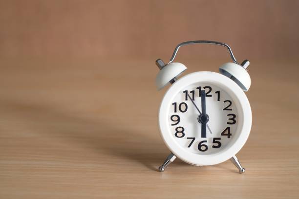 istock White Alarm Clock on wooden background 873572332