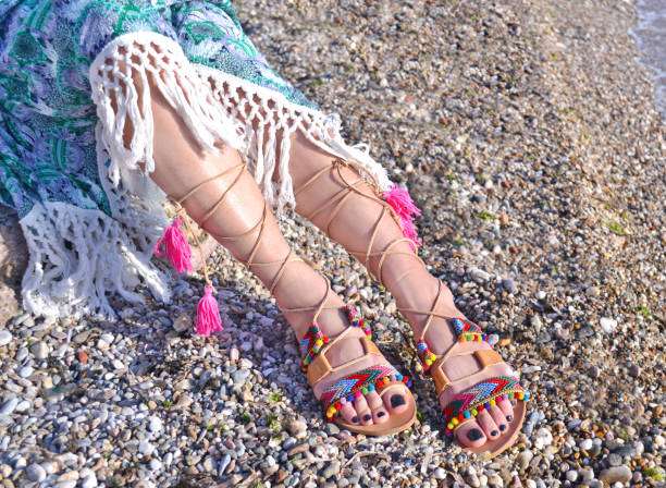 leather greek sandals advertisement on the beach leather greek sandals advertisement on the beach - bohemian style clothing gladiator shoe stock pictures, royalty-free photos & images