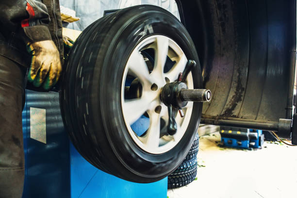 istock Mechanic balancing wheel with computer machine balancer at car service garage workshop 873584922