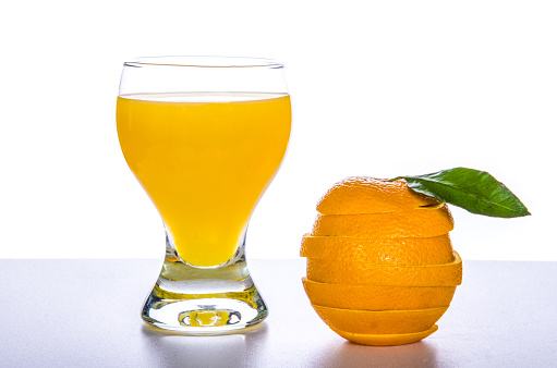 glass with orange juice, a cut orange on a fresh table and a white background