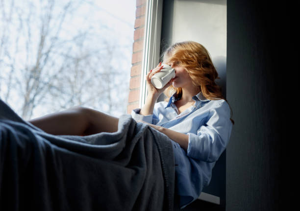 istock Sad woman by the window. 873587358