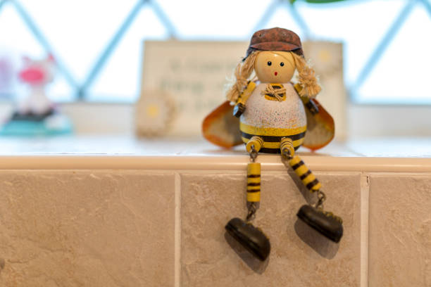 istock Cute tiny lady female bee artisan character ornament or toy sitting on a tiled window ledge 873590006
