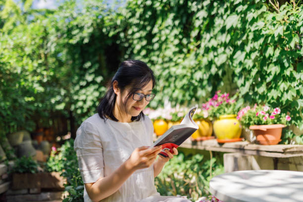 chinese woman reading book - woman with glasses reading a book imagens e fotografias de stock