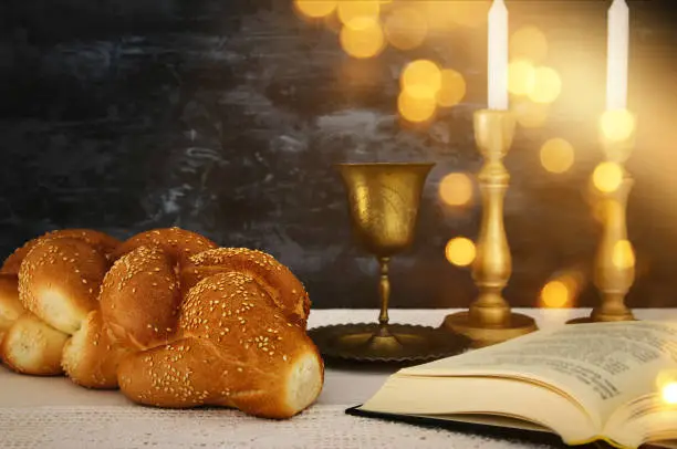 shabbat image. challah bread, shabbat wine and candles on the table.