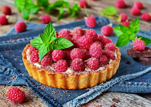 Delicious raspberry tart with fresh raspberries and mint on a beautiful background