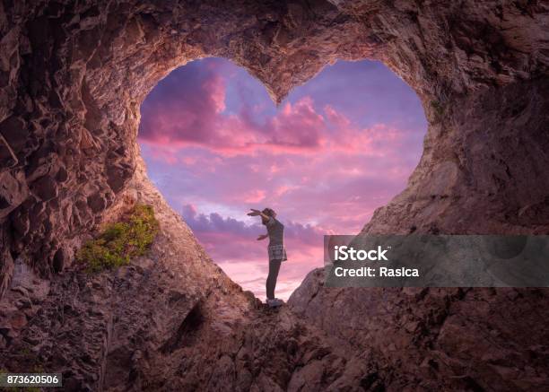Young Woman In Heart Shape Cave Towards The Beautiful Sky Stock Photo - Download Image Now