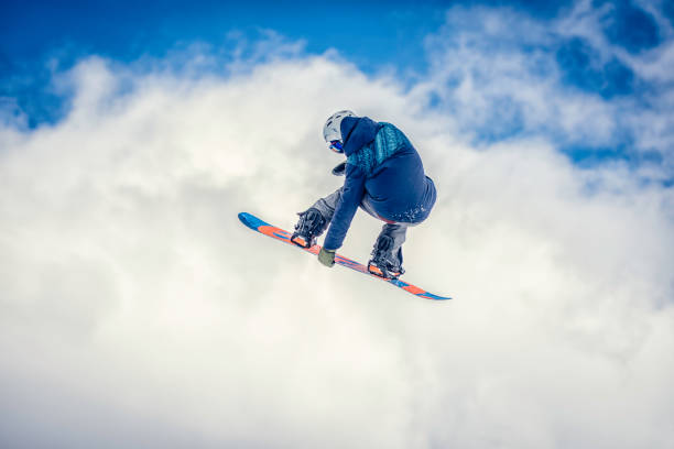 Rear view of a snowboarder on a cloudy background doing a melon grab.