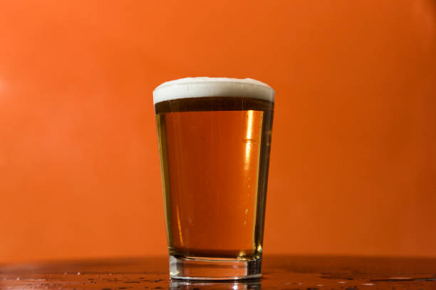 istock Pilsener beer glass in orange color background 873635432