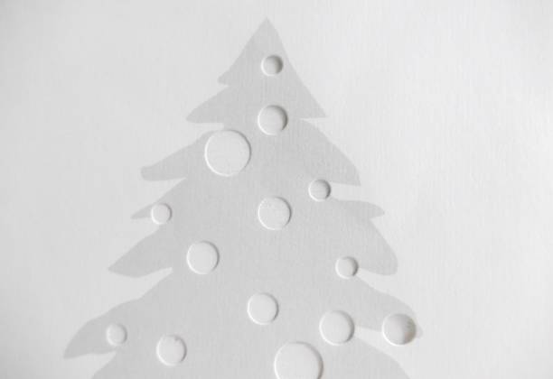 Gray  paper christams tree full of holes on white wall